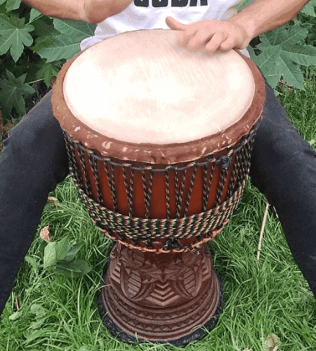 Drummer demonstrating how to hold a djembe drum for West Africa rhythm
