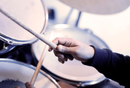 hands of drummer holding drumming sticks just about to play a drumset